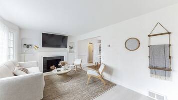 Ein modernes Wohnzimmer mit Kamin, Fernseher und Essbereich.