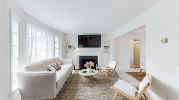 A spacious living room with a fireplace, a sofa, a coffee table, and two chairs.