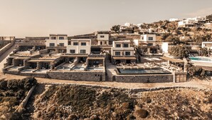 Un village côtier doté de bâtiments blancs modernes, de structures en terrasses et d’une piscine.
