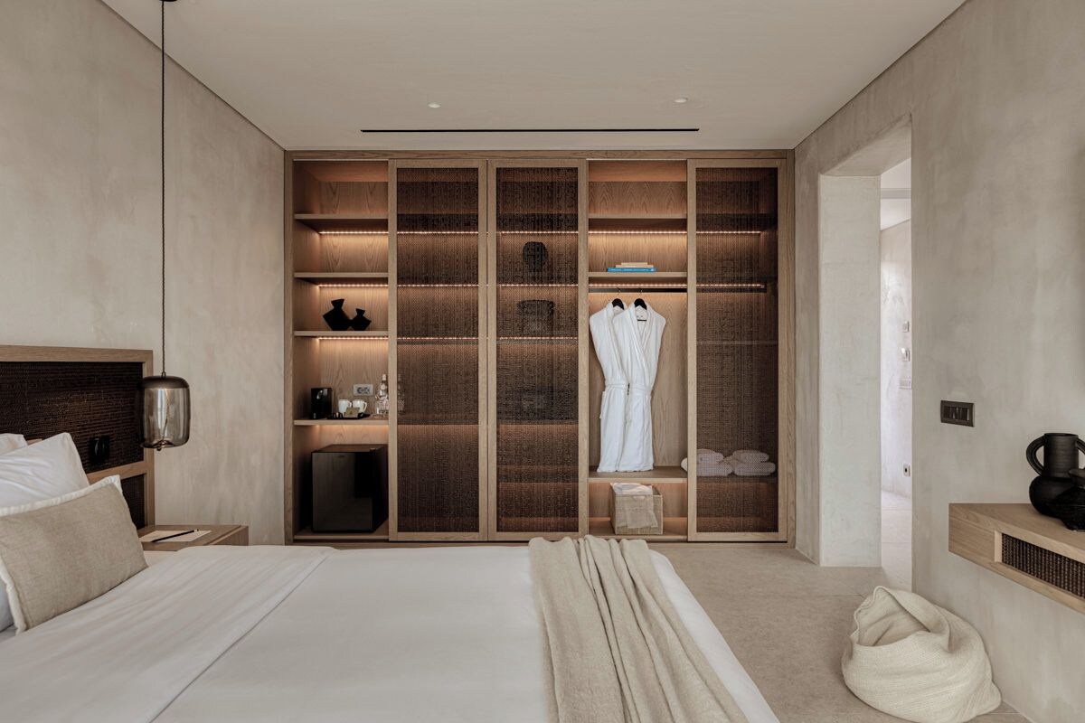 Une chambre à coucher moderne avec un grand lit, un dressing avec étagères et une table de chevet.