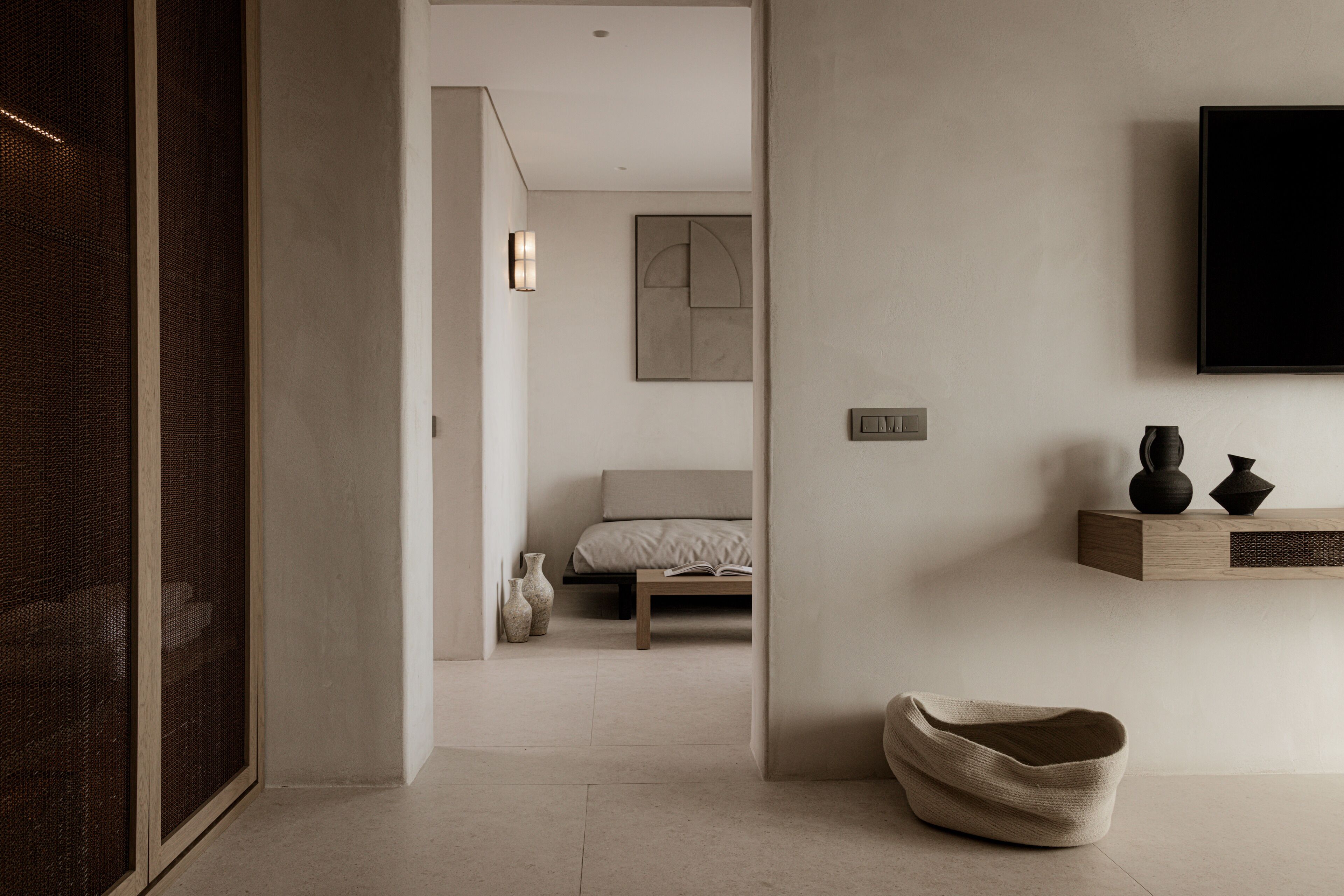 Un dormitorio moderno con cama, mesita de noche y televisor montado.