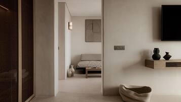 Un dormitorio moderno con cama, mesita de noche y televisor montado.