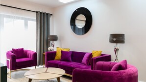 A modern living room with a purple sofa set, a round mirror, and two floor lamps. - Designer 2-bed 2-bath apartment with a garden (London)