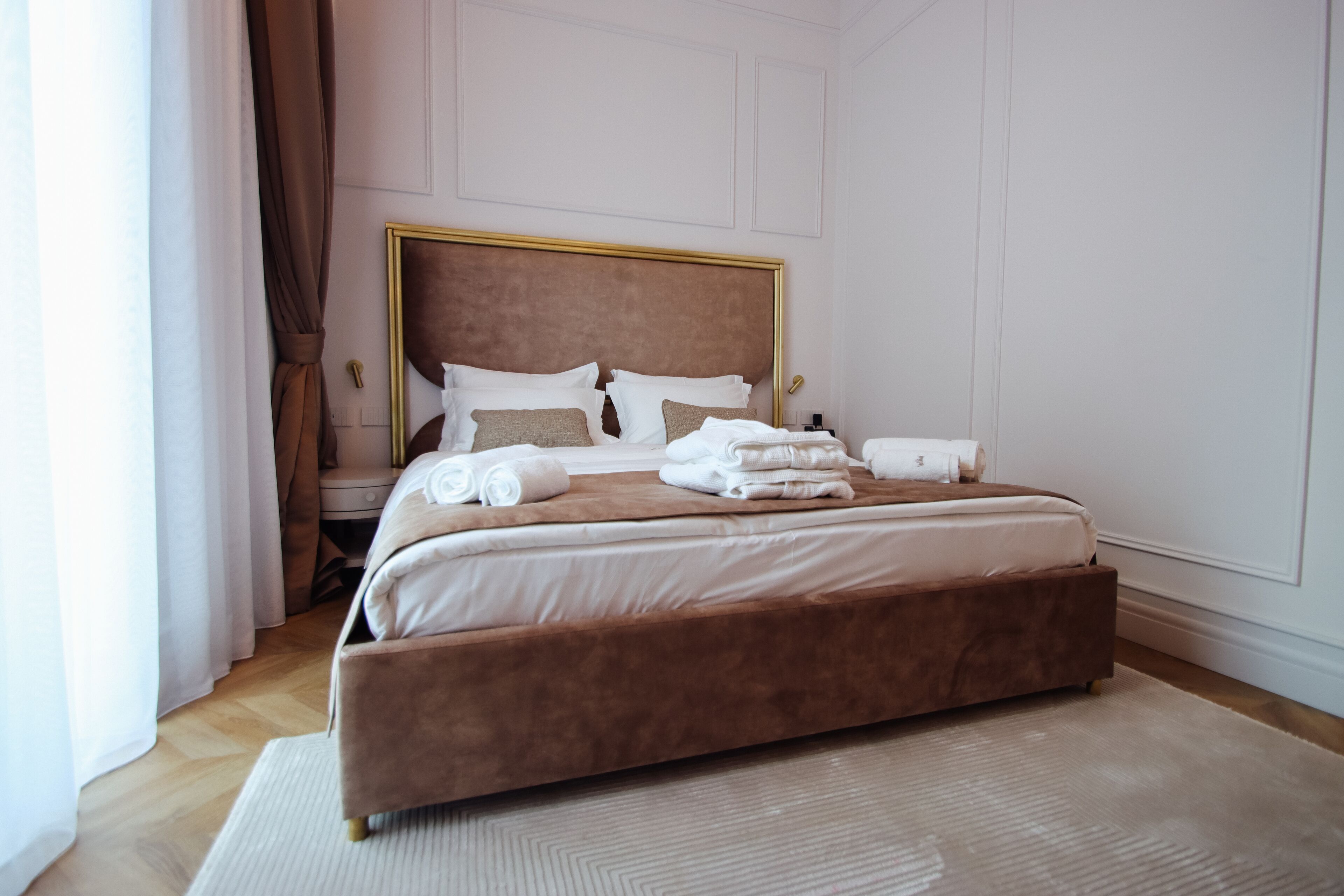 A large bed with a wooden headboard, white linens, and a brown accent.