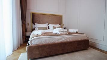 A large bed with a wooden headboard, white linens, and a brown accent.