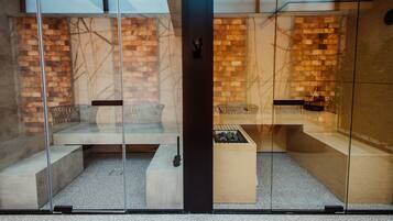 A modern interior with glass partitions, a brick wall, and a seating area with a small table and bench.