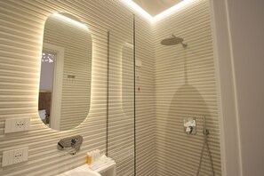 Un baño moderno con un espejo grande, ducha y lavabo.