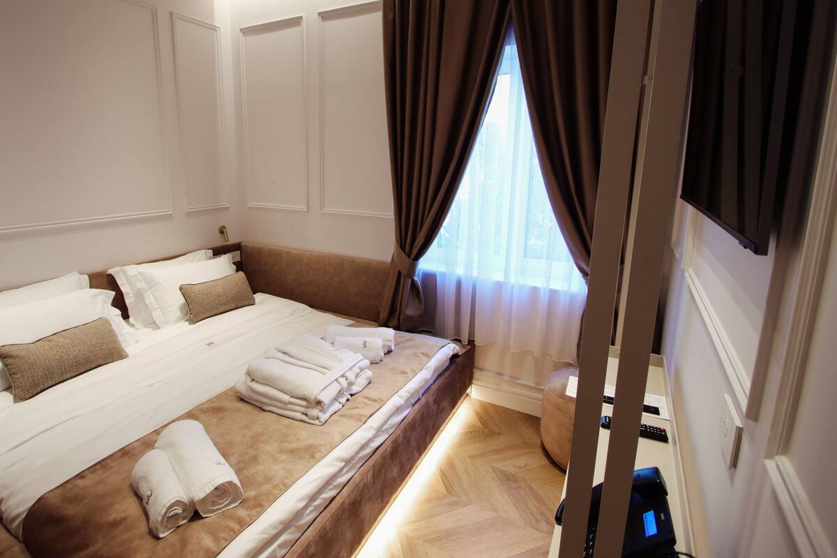 Habitación de hotel con una cama grande, toallas ordenadamente dobladas y vistas al exterior a través de la ventana.