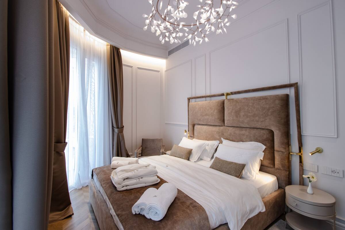 Una habitación de hotel moderna con una cama grande, una mesita de noche y un candelabro.