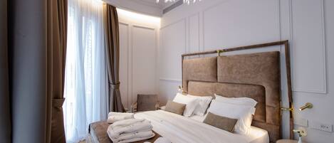 A modern hotel room with a large bed, a bedside table, and a chandelier.