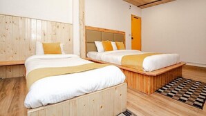 A hotel room with two beds, wooden headboards, and a checkered rug. - Hotel Beas regency (Manali)