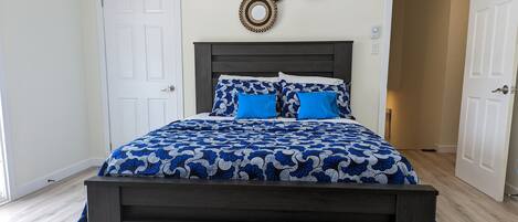 Une chambre à coucher avec un cadre de lit en bois foncé, une couvre-lit bleue et blanche à motifs et des coussins assortis. Deux éléments de décoration circulaire sont accrochés au mur au-dessus du lit.