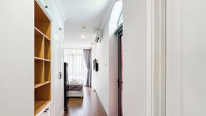 A hallway with a wardrobe, a bed, and a door leading to a balcony. - Golden Sun Hotel Apartments (Ho Chi Minh City)