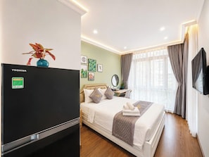 Habitación de hotel con cama, escritorio, televisor de pantalla plana y planta.