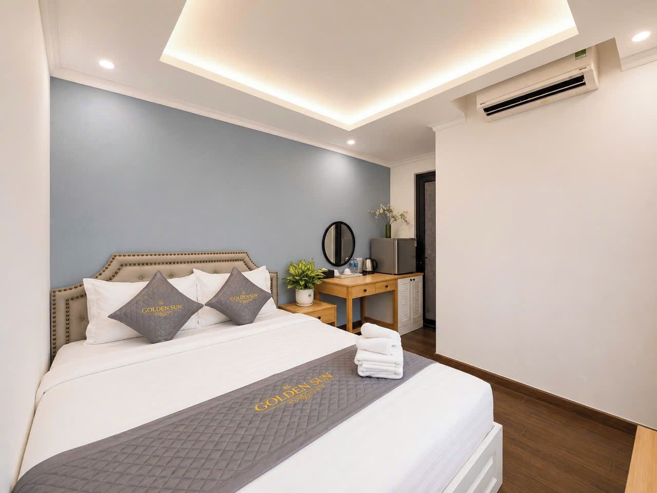 A hotel room with a bed, bedside table, and a desk with a chair.