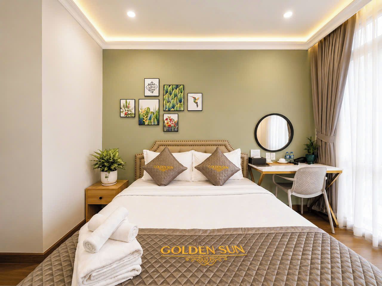 A hotel room with a bed, a desk, and a chair. There are pillows with the hotel's name on them.