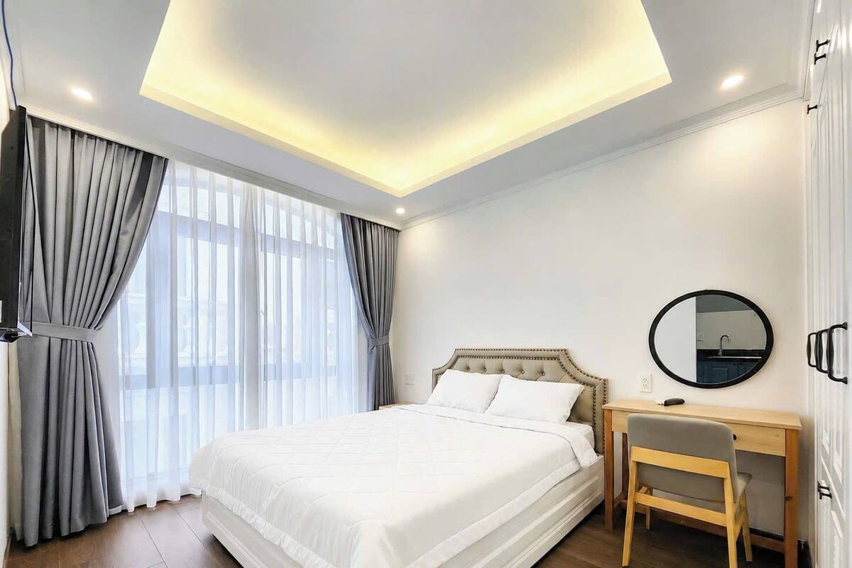 A modern hotel room with a large bed, a desk, and a mirror.