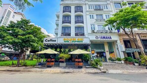 A hotel with a sign for 'Golden Sun Hotel & Apartments' and a 'Coffee' shop in front. - Golden Sun Hotel Apartments (Ho Chi Minh City)