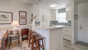 A compact kitchen with a central island, bar stools, a dining area with a wicker table, and a large mirror above the island. - Secluded, yet close to everything Port A has to offer. Sit on the deck and watch (Port Aransas)