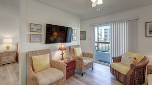 A living room with wicker furniture, a flat-screen TV, and a balcony with a view of buildings. - Secluded, yet close to everything Port A has to offer. Sit on the deck and watch (Port Aransas)