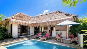 A poolside area with a thatched-roof structure, lounge chairs, and a small table. - Villa with all comforts, close to the most beautiful spots on the island (ungasan)