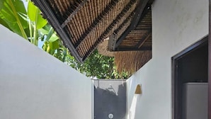A narrow pathway leading to a dark door, surrounded by white walls and a thatched roof structure. - Villa with all comforts, close to the most beautiful spots on the island (ungasan)