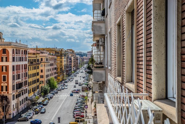 Vista de la calle con edificios a ambos lados, cielo despejado y coches estacionados.