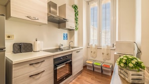 Una cocina moderna con armarios de madera clara, electrodomésticos de acero inoxidable, horno empotrado y ventana con vistas.