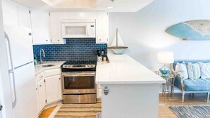 Una cocina moderna con armarios blancos, salpicadero azul, electrodomésticos de acero inoxidable y una isla central.