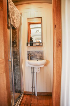 Ein Badezimmer mit Dusche, Waschbecken und Holzvertäfelung.