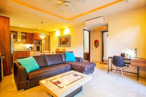 A modern living room with a sofa, coffee table, and a dining area with a table and chairs. - Serene 1BR w/ Patio & Workspace (Puerto Vallarta)