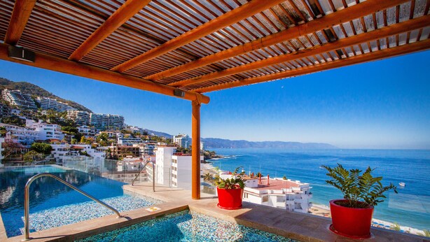 En pool på taket med fri utsikt över havet och de omgivande byggnaderna.