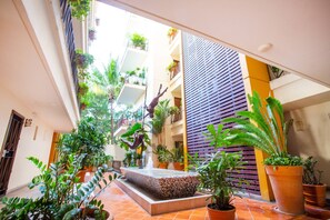 A multi-level indoor courtyard with potted plants, a central fountain, and a statue. - Serene 1BR w/ Patio & Workspace (Puerto Vallarta)