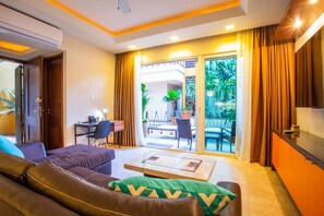 A modern living room with a sofa, a coffee table, and a dining area with chairs and a table. - Serene 1BR w/ Patio & Workspace (Puerto Vallarta)