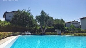 Une piscine aux eaux cristallines, entourée de verdure et de bâtiments.