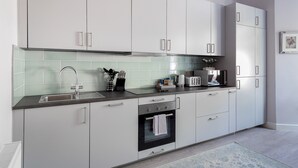 Eine moderne Küche mit weißen Schränken, einer Edelstahlspüle und einem eingebauten Backofen.