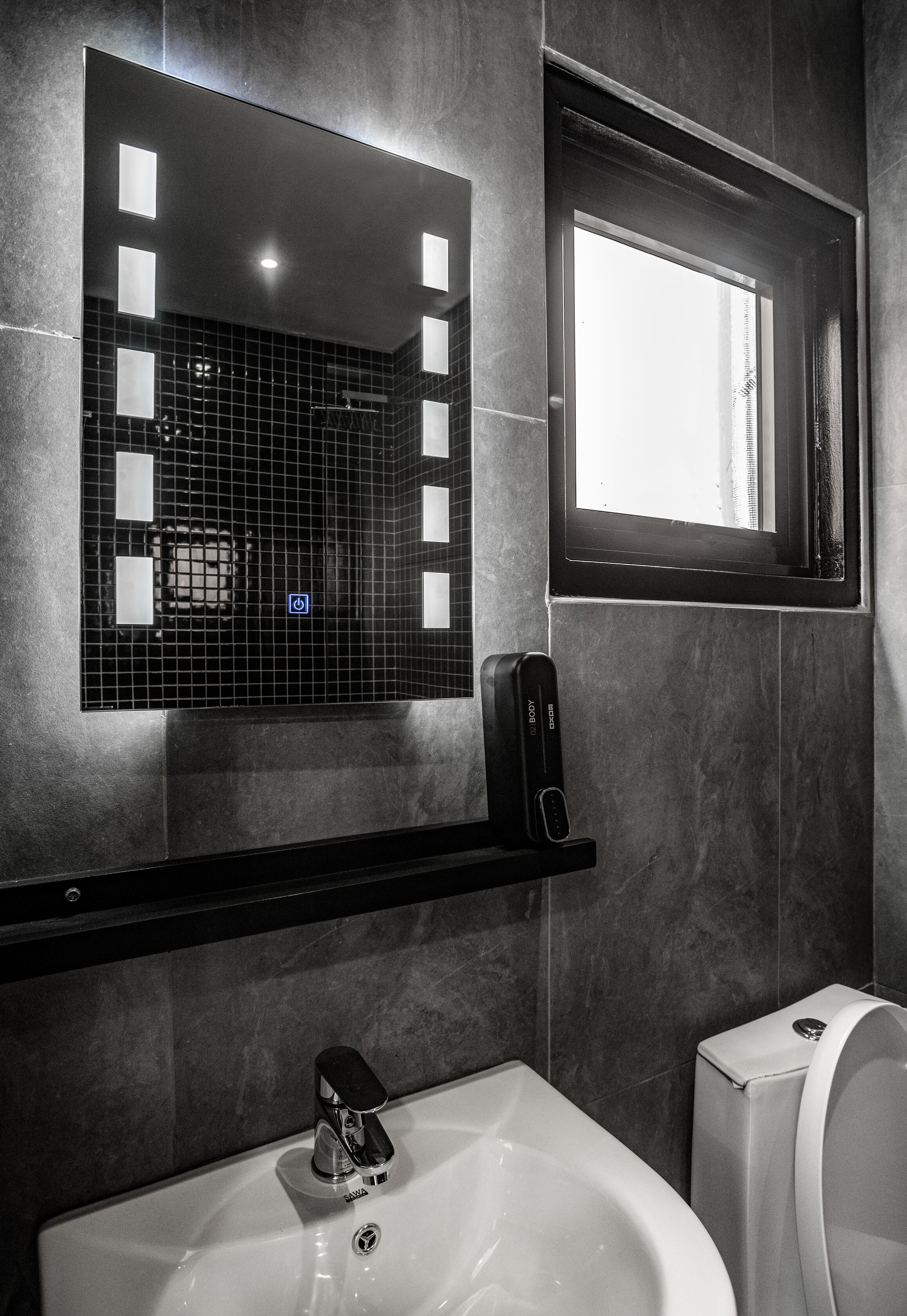 A modern bathroom with a large mirror, a hand dryer, and a toilet.