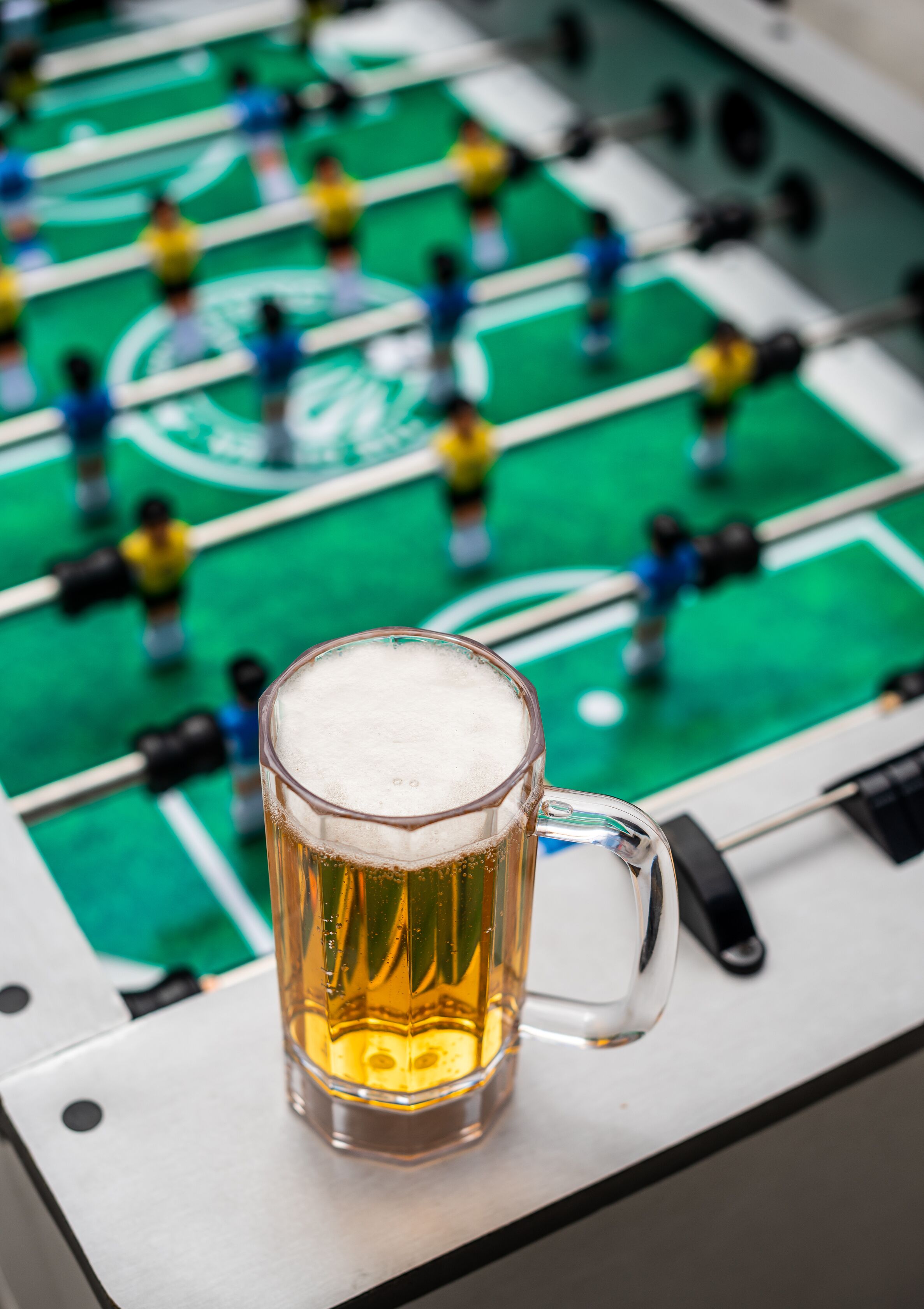 A foosball table with a glass of beer in the foreground.
