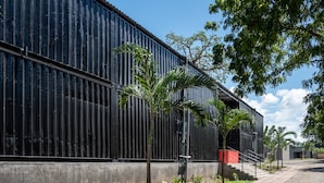 A modern building with a metal exterior, a concrete base, and a pathway leading to a staircase. - Boxo Diani (Diani Beach)