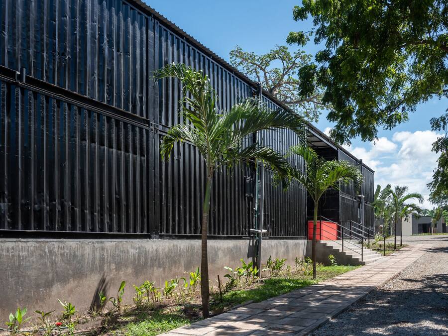 A modern building with a metal exterior, a concrete base, and a pathway leading to a staircase.