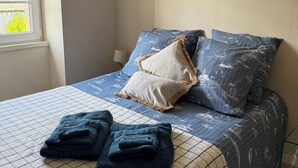 A bedroom with a bed, pillows, a blanket, and two paintings on the wall. - La Maison De Marraine indoor jacuzzi (Kerlouan)