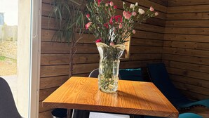 A wooden interior with a table and chairs, a vase with flowers, and a view through a glass door. - La Maison De Marraine indoor jacuzzi (Kerlouan)