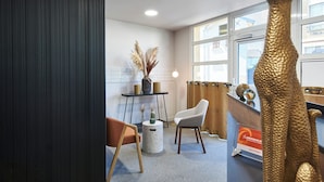 A reception area with a desk, a chair, a vase with pampas grass, and a gold sculpture. - Logis Hôtel Larivaut, Puy-Guillaume (Puy-Guillaume)