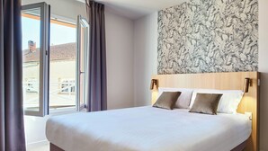 A hotel room with a large bed, a wooden headboard, and a view through a sliding door to the outside. - Logis Hôtel Larivaut, Puy-Guillaume (Puy-Guillaume)