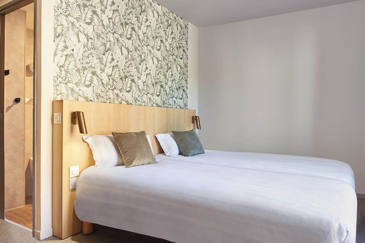 A bedroom with a bed, a wooden headboard, and a floral-patterned wall.