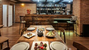 A modern dining area with a brick wall, wooden table, and hanging pendant lights. - Reed Hotel Tbilisi (Tbilisi)