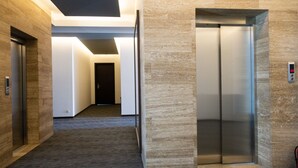 A hallway with two elevators, carpeted flooring, and a door at the end. - Reed Hotel Tbilisi (Tbilisi)