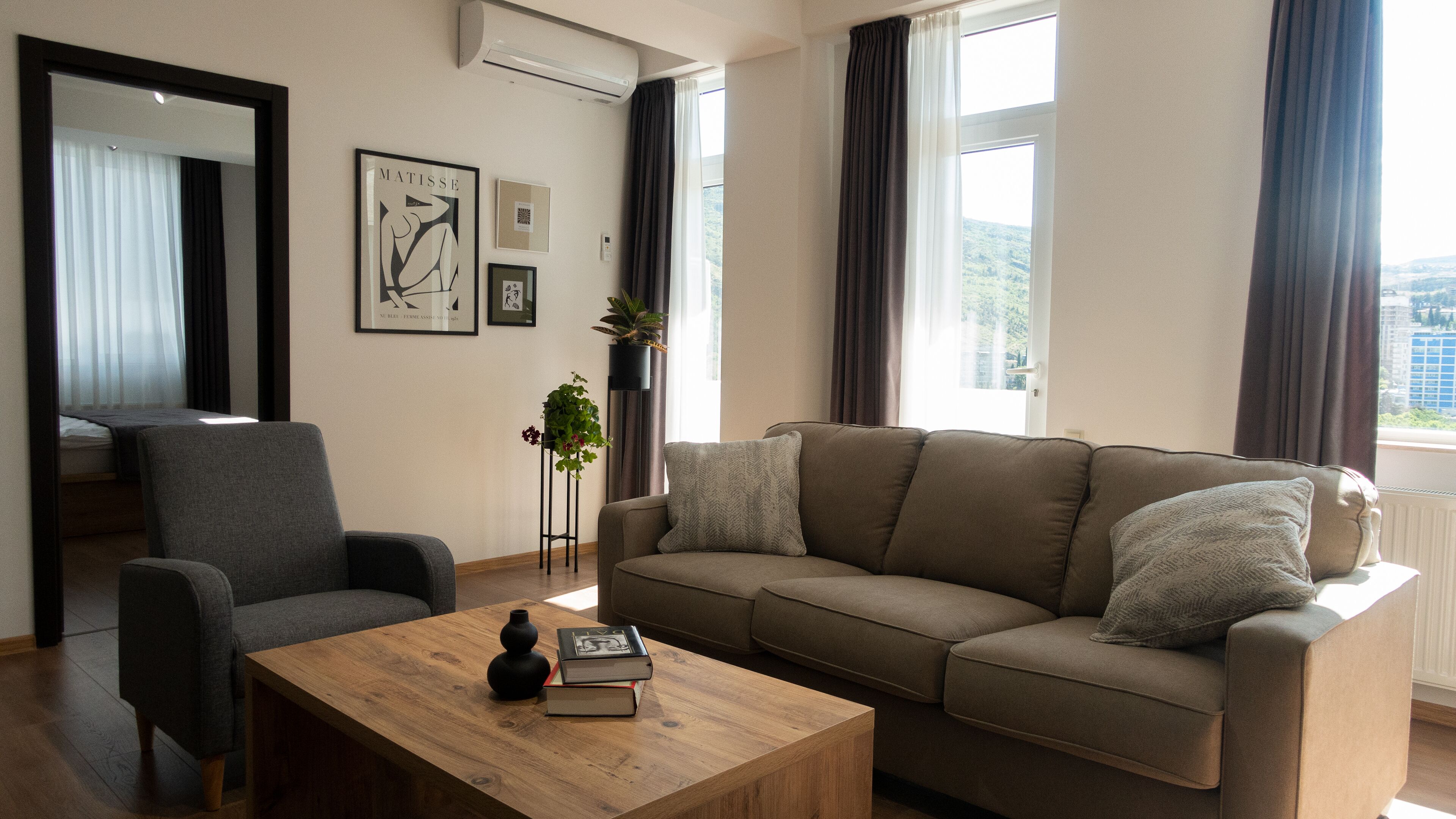 A living room with a sofa, armchair, coffee table, and artwork on the wall.