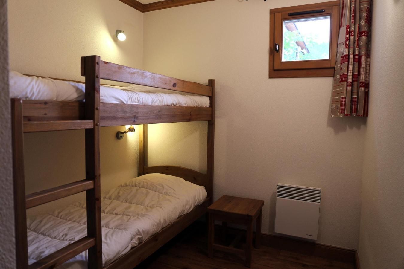Quarto com beliche, uma mesinha e aquecedor.