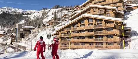 A ski resort with wooden buildings, ski slopes, and a clear sky.